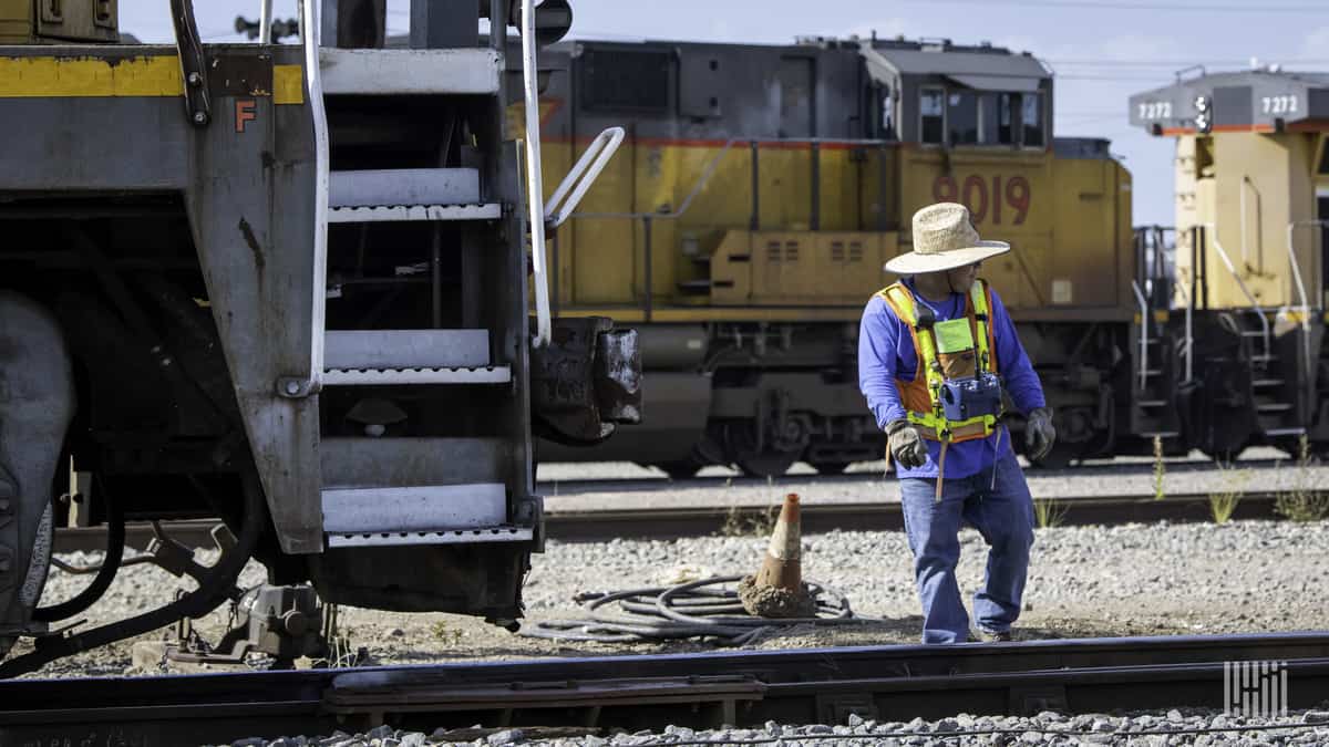 A photograph of a man working in a rail yard.