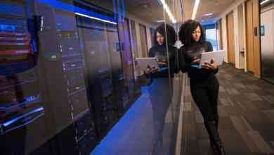 Woman standing outside server room holding laptop