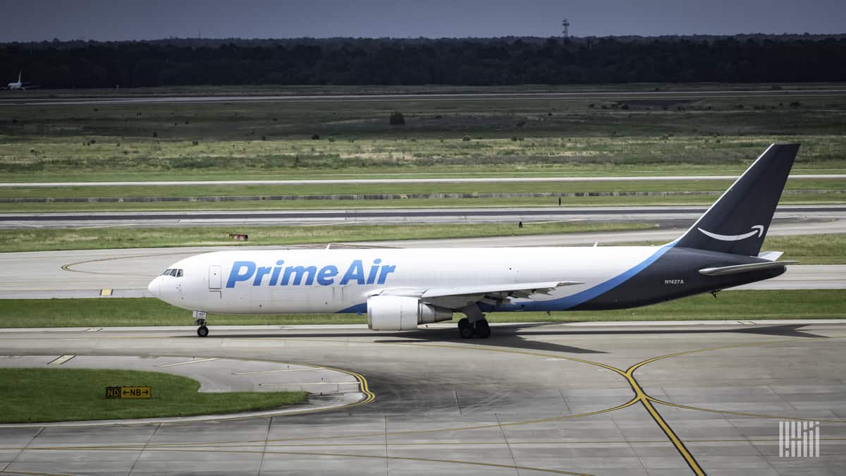 A white Amazon Air jet with blue tail, side view on runway.