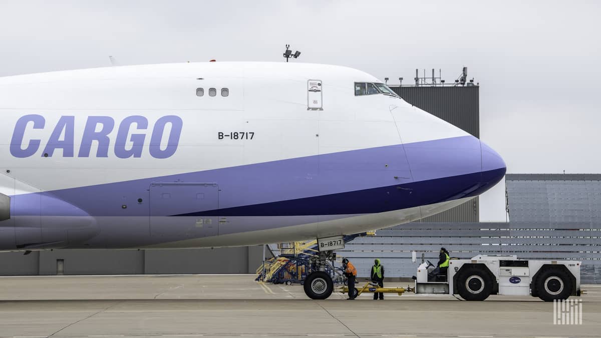 A 747 jumbo jet with white paint and light blue accents with the word CARGO on the side.