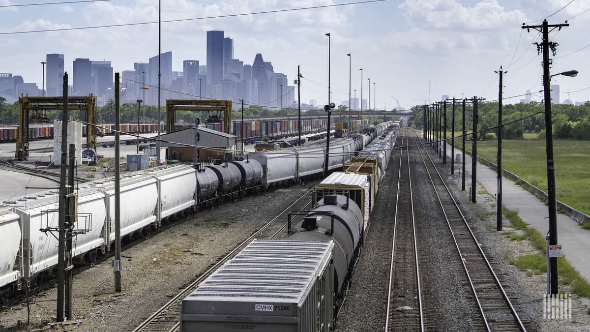 A photograph of a rail yard. A city is in the distance.