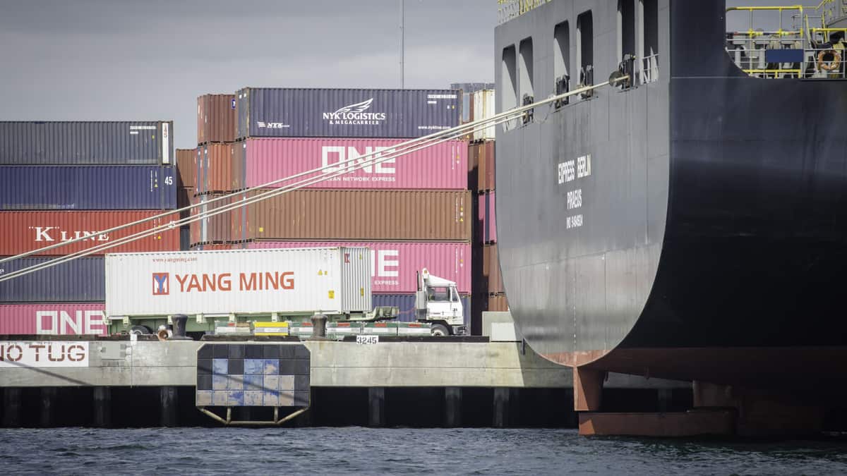 Waterside view of docks stacked with containers and back of a big ship.