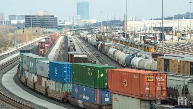 A photograph of a rail yard with a city skyline in the distance.
