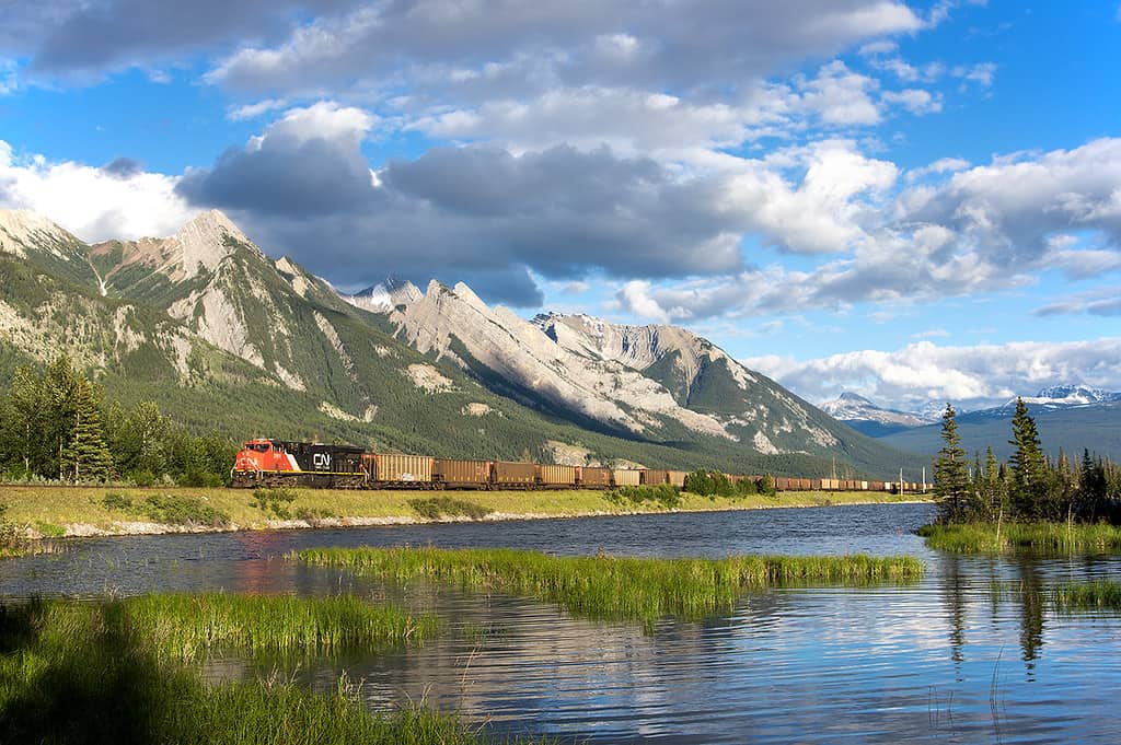 A photograph of a CN train passing by a mountainside lake.