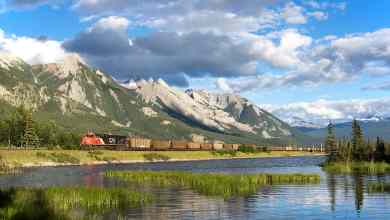 A photograph of a CN train passing by a mountainside lake.