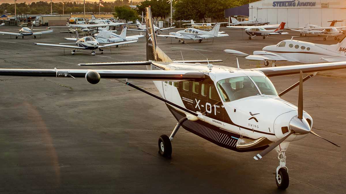 A propeller plane sits in the parking lot of a general aviation airport.