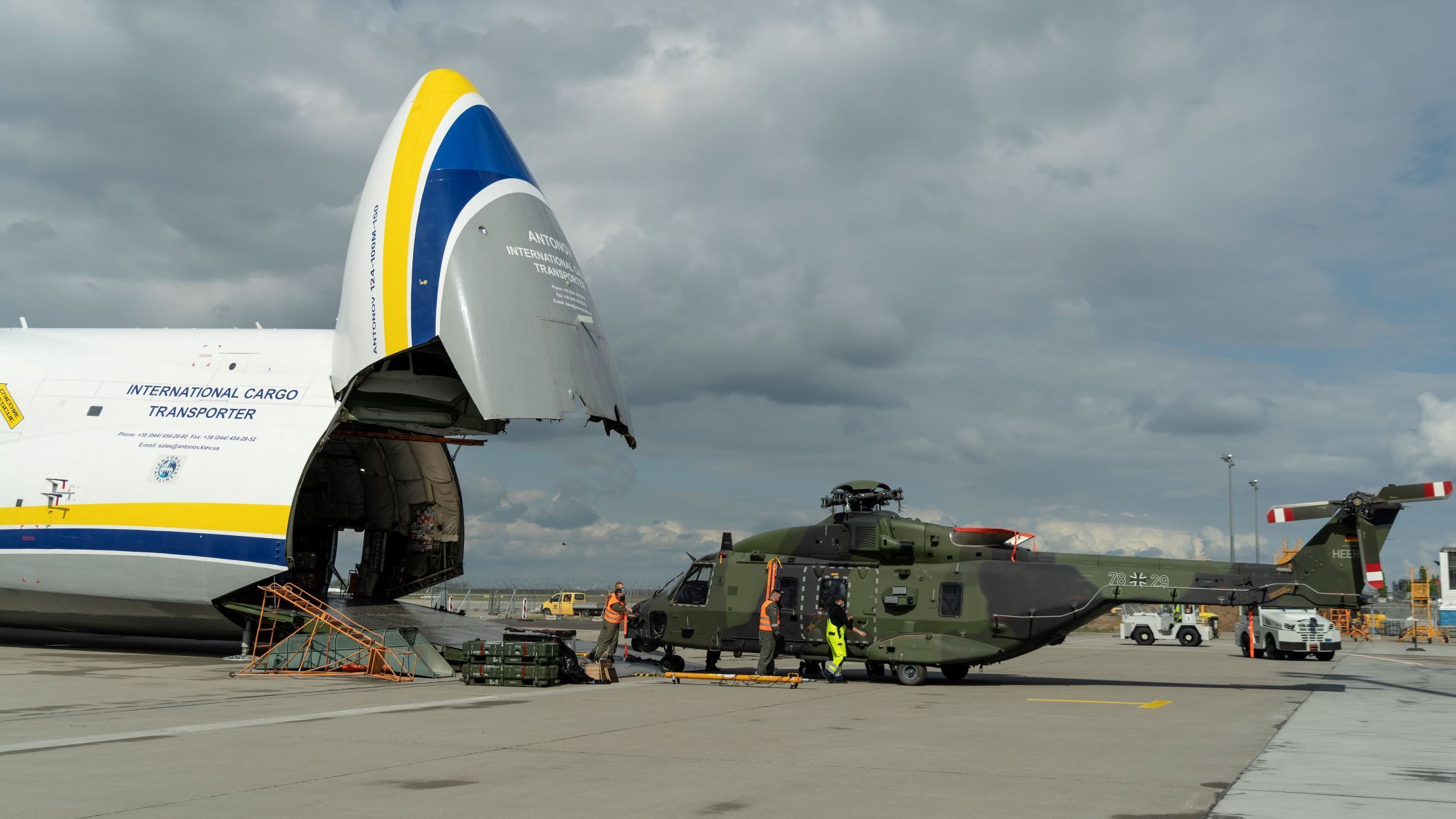 A giant nose-loading plane and a helicopter in front after being removed from the plane.