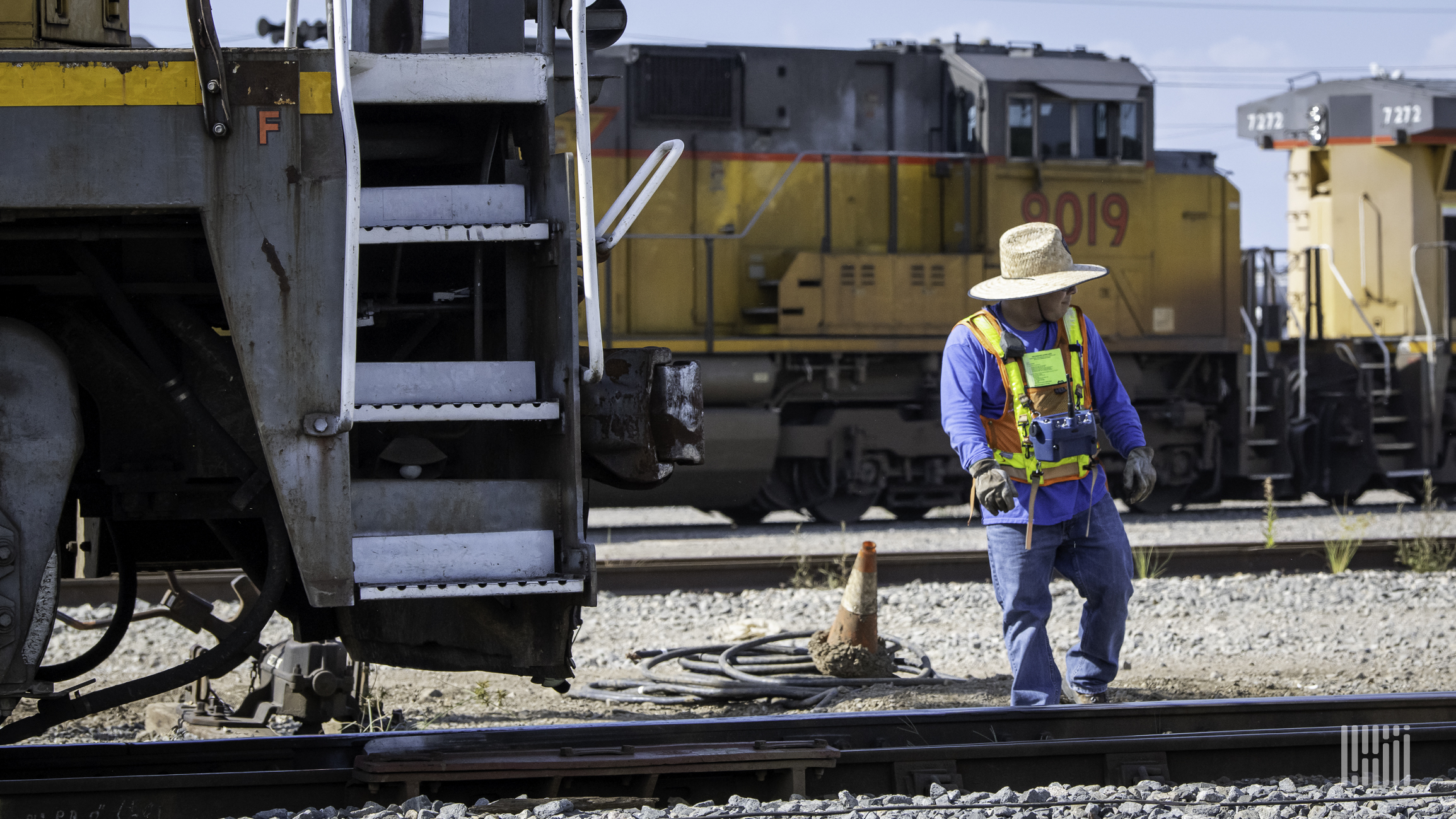 A railroad worker stands in a rail yard.