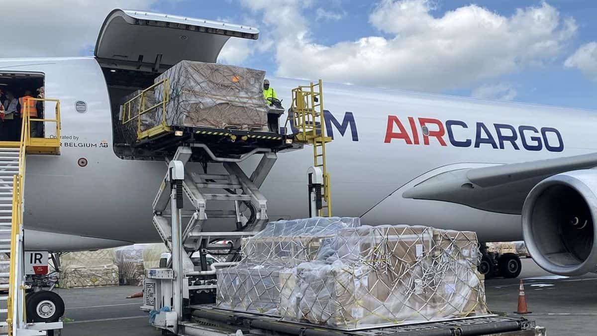 A white airplane with AIR CARGO written on the side gets loaded through side door.