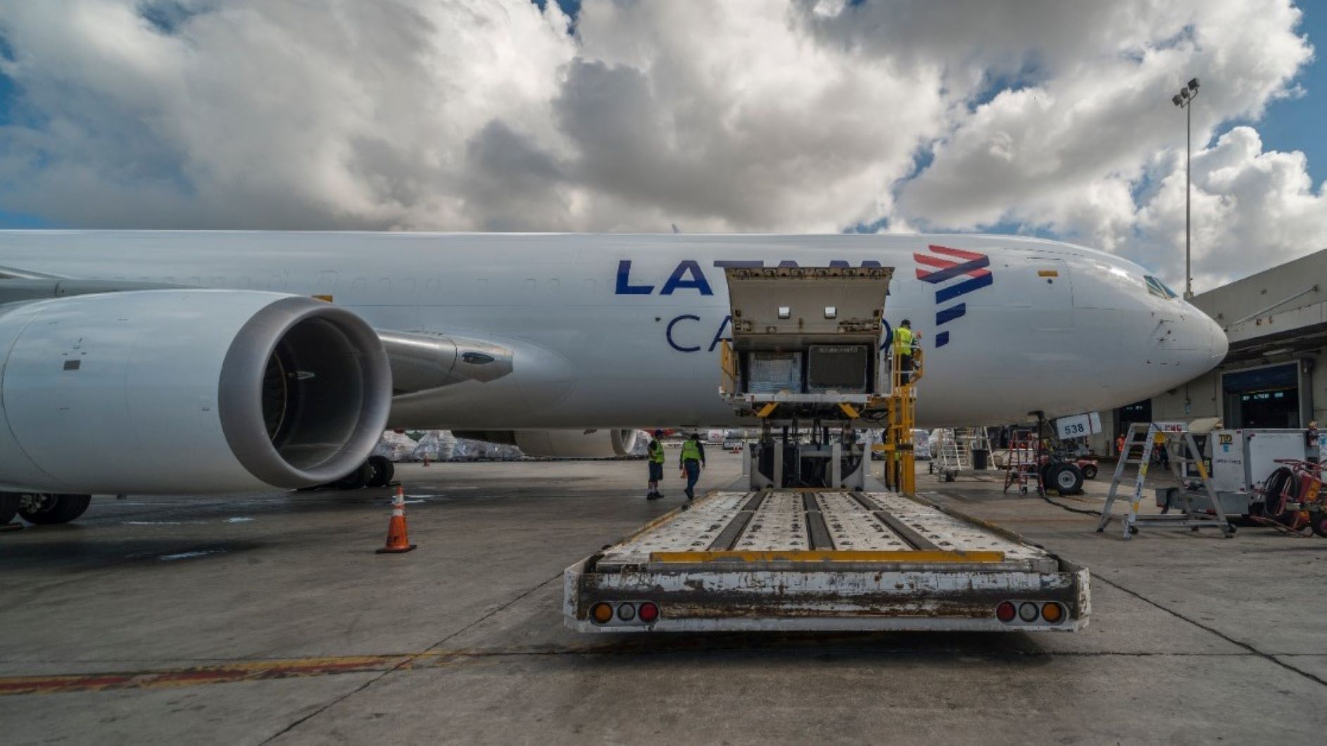 Side view of a white cargo jet with the side door wide open and a dolly in the foreground.