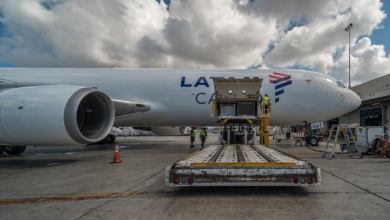 Side view of a white cargo jet with the side door wide open and a dolly in the foreground.