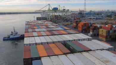 A tugboat helps park a large containership at the Port of Montreal. by pushing it into the wharf.