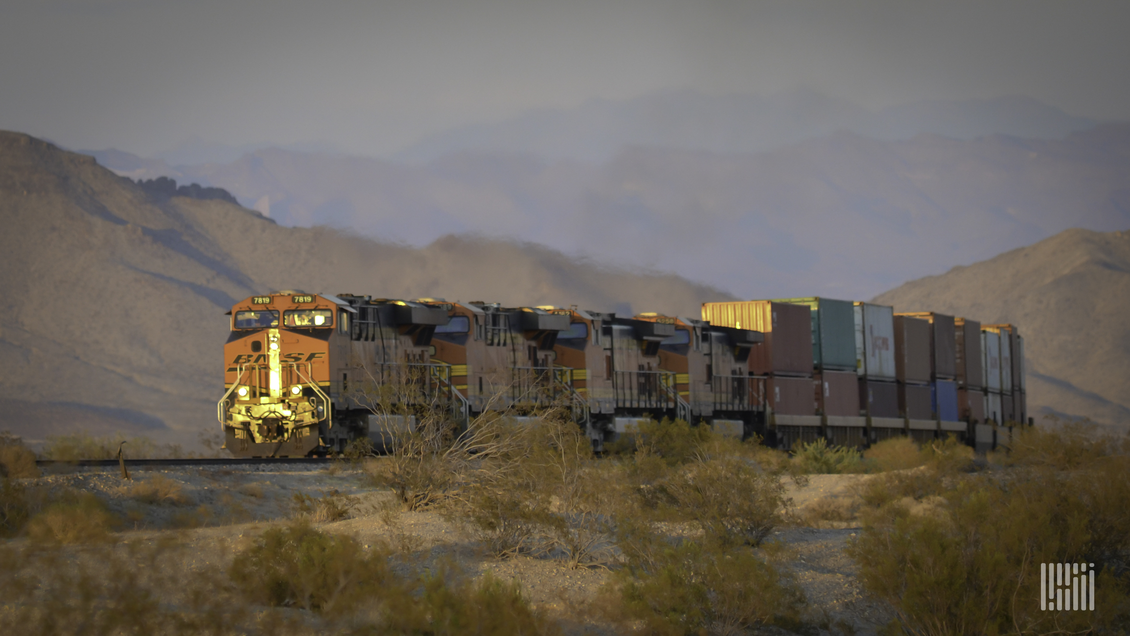 A photograph of a BNSF train hauling intermodal containers across a field.