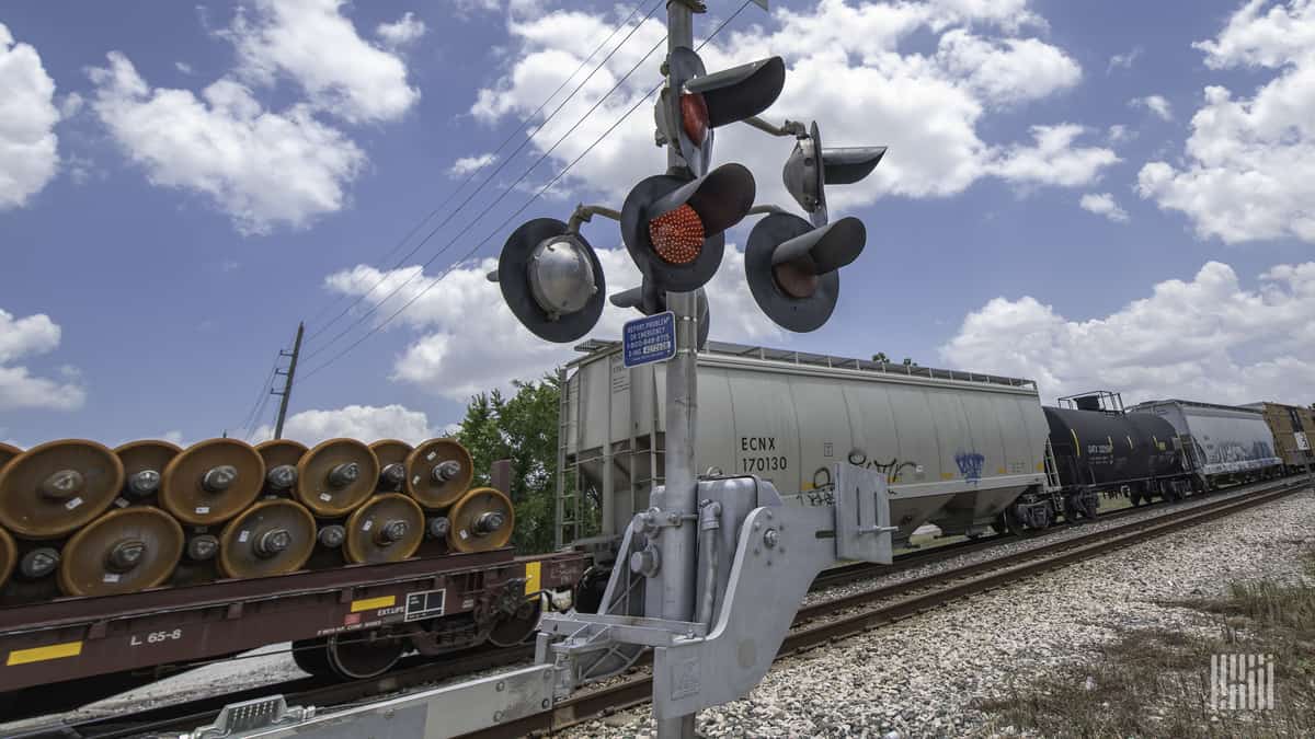 A photograph of a train at a railroad crossing.