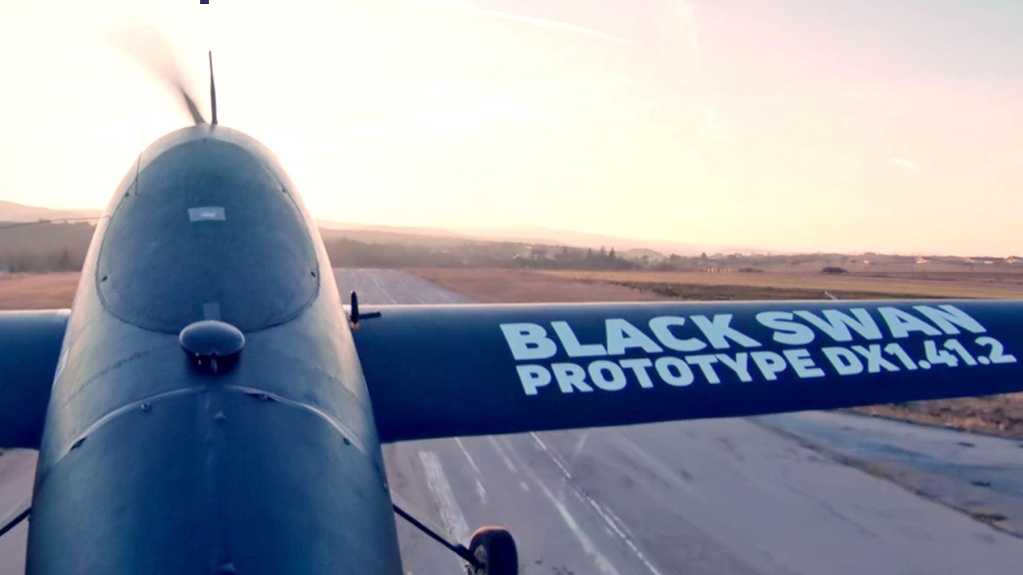 A close up of a winged, cargo drone from top of fuselage looking forward on runway.