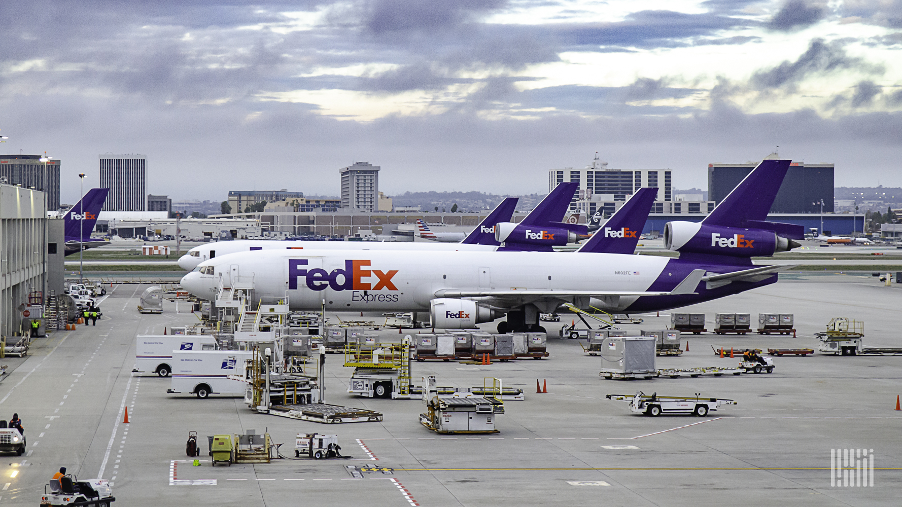 Several FedEx planes lined up at an airport terminal.