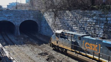 A photograph of a CSX train heading into a tunnel.