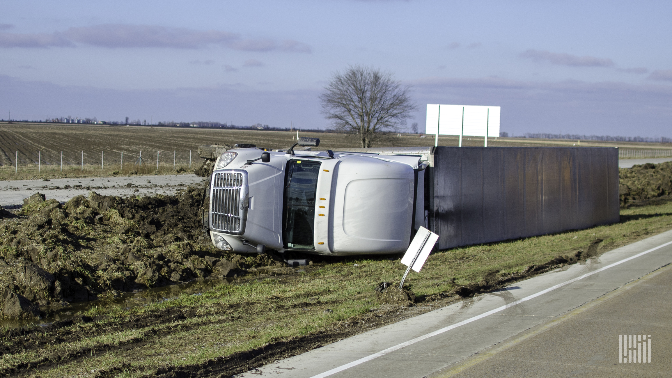 Tractor-trailer flipped on the side of a road.