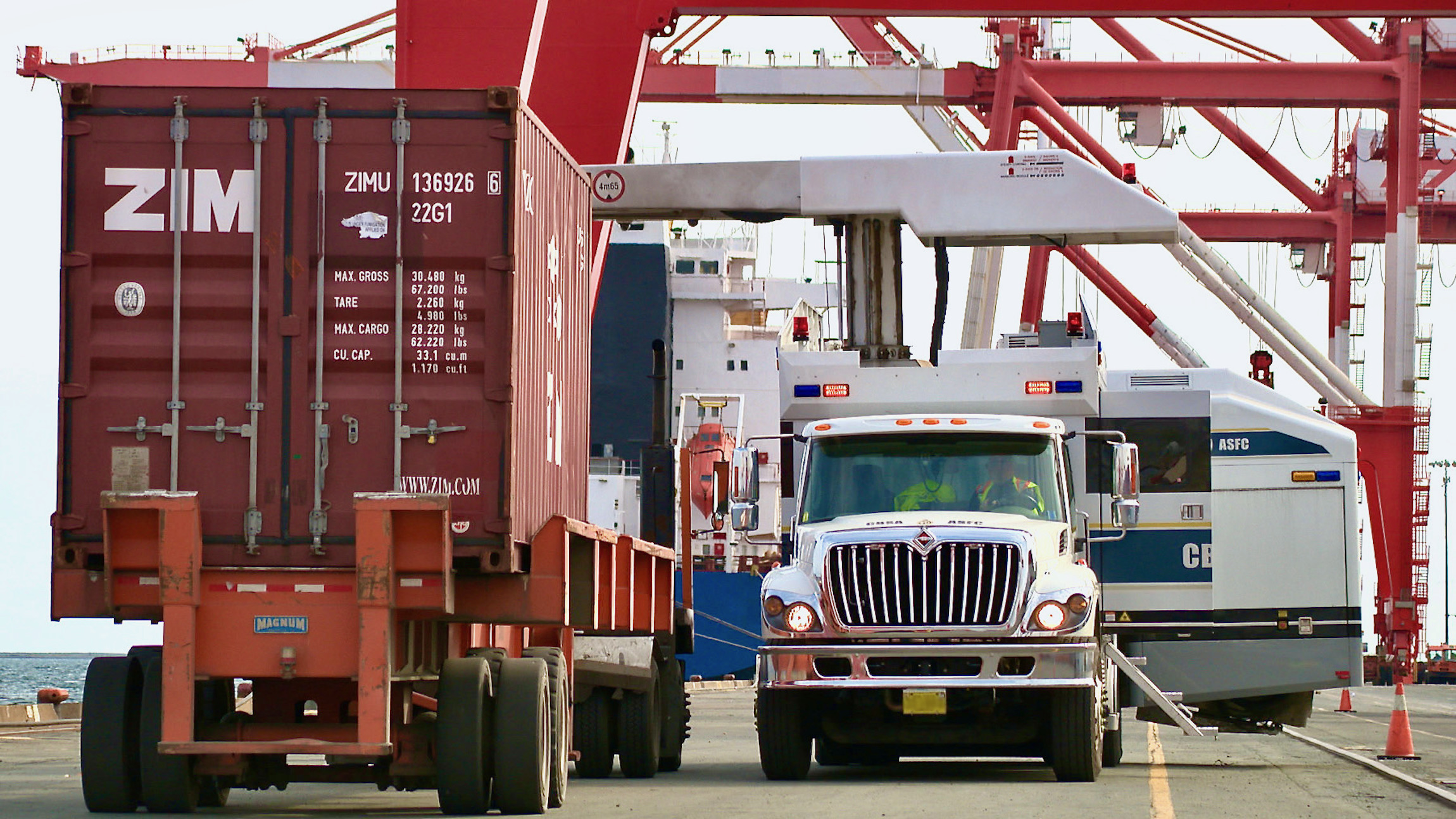 Canada Border Services Agency officers prepare to inspect a red intermodal container.