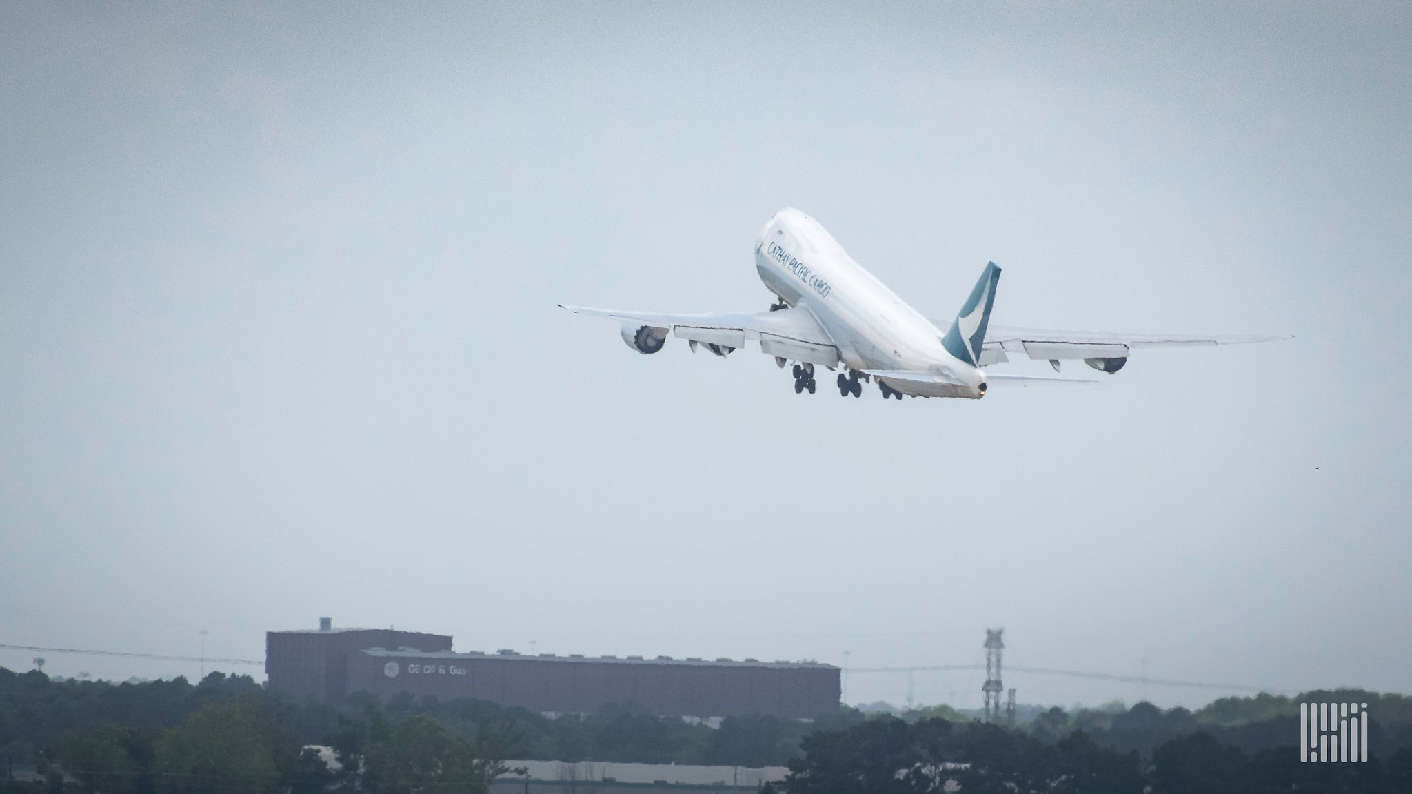 A jumbo jet takes off into a gray sky. View from behind.