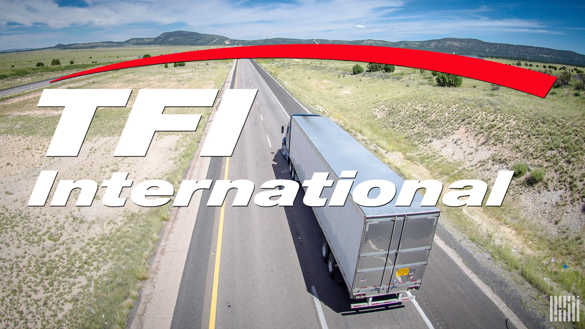 A commercial truck seen from behind travels on a highway with the logo of TFI International layered on top of the image.