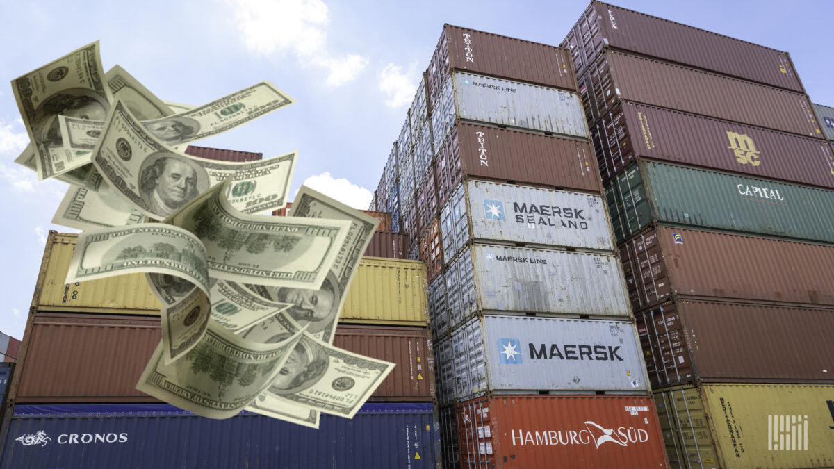 A stack of ocean freight containers with dollar bills added to image to show how expensive shipping has become.