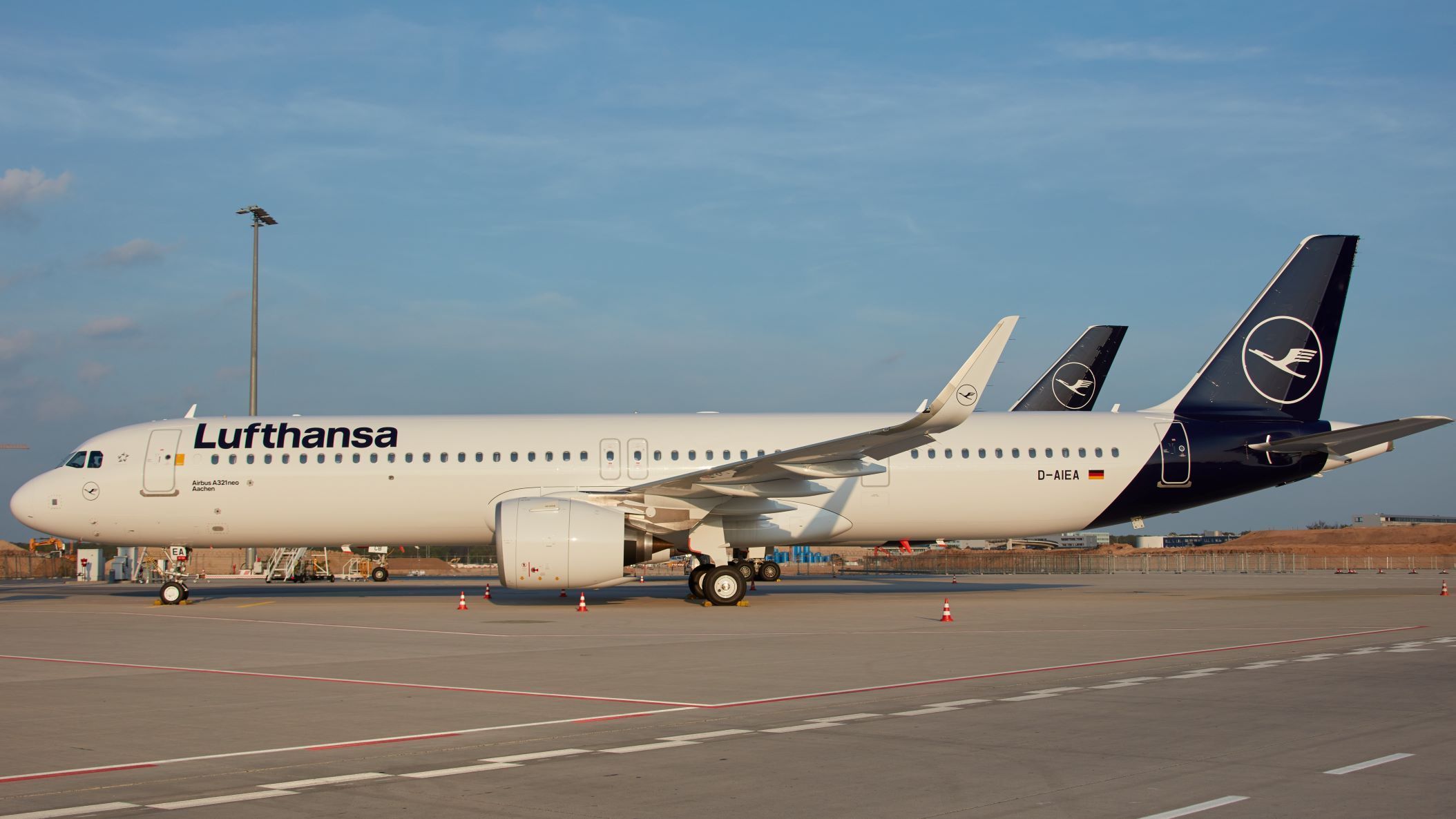 A white Lufthansa plane with blue tail.