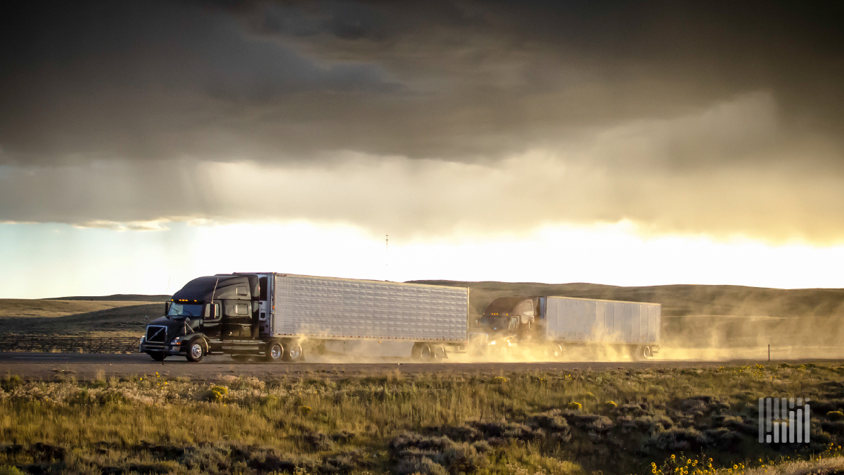 Tractor-trailer heading down desert highway in the rain.