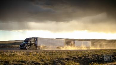 Tractor-trailer heading down desert highway in the rain.