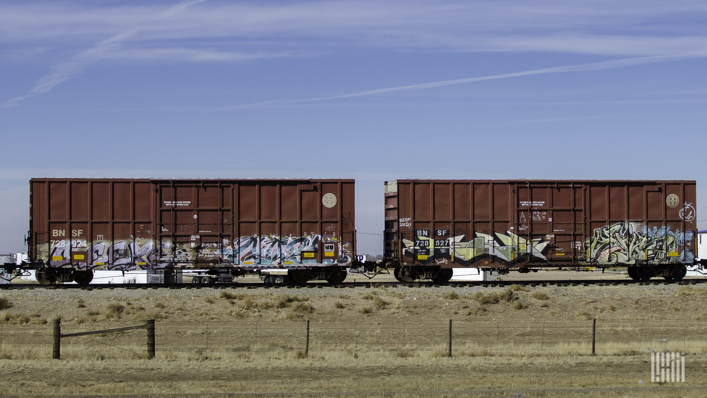 A photograph of two boxars rolling down train track.