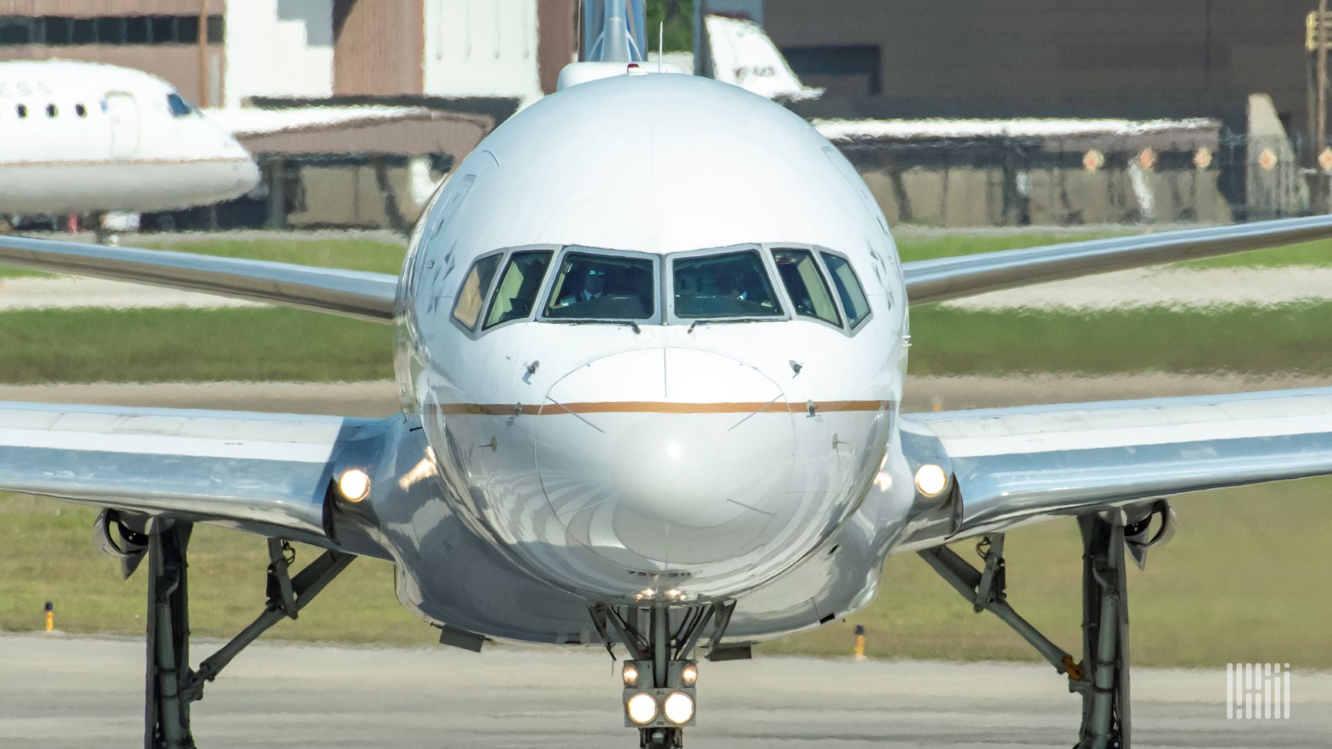 Close up of white jet staring right at nose and cockpit on the ground.