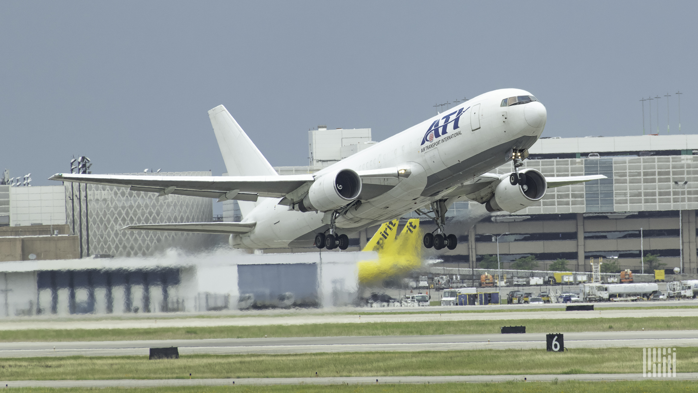 A big white jet with ATI lettering lifts off from runway.
