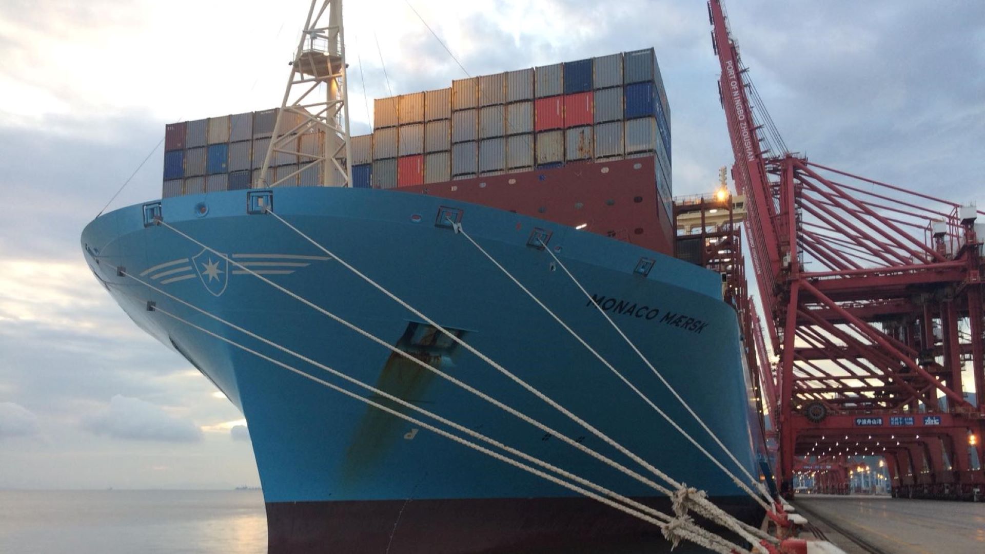 A big vessel tied up at the dock, view from the bow with ropes in the foreground.