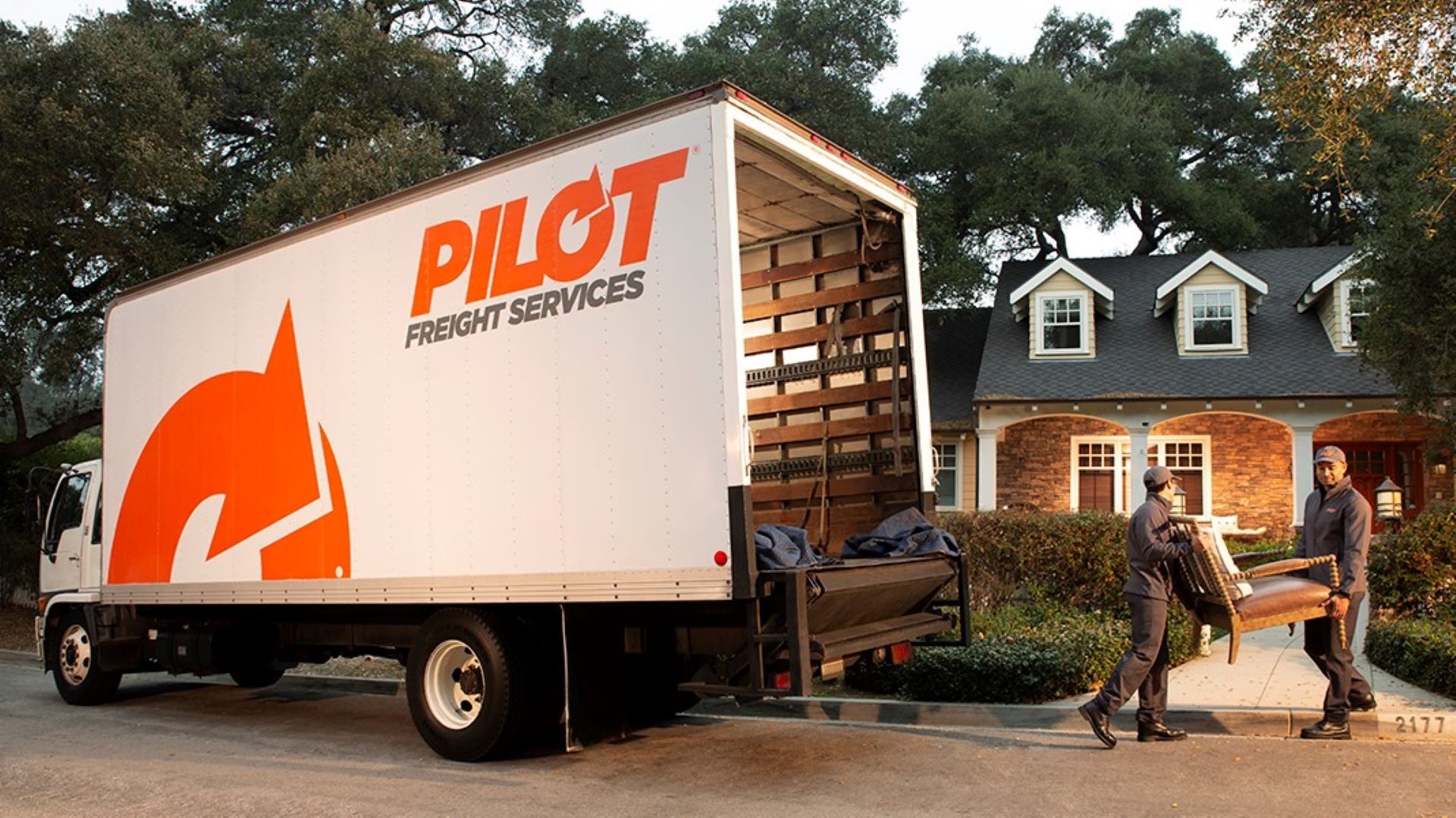 Drivers unload furniture from a truck to bring in a home. Pilot Freight is the company.