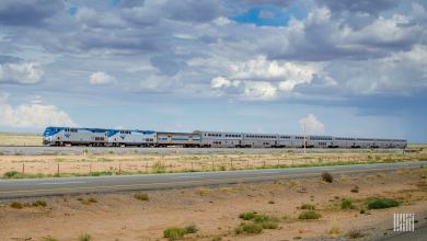 A photo of an Amtrak train travelling through a flat and grassy plain.