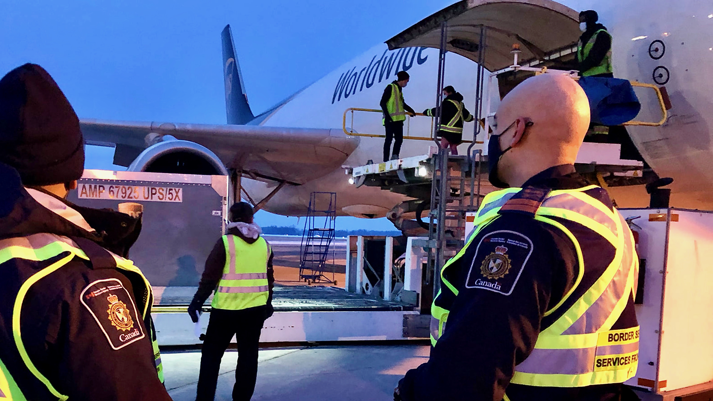 Canada Border Services Agency officers look on as cargo is unloaded from a UPS cargo flight.