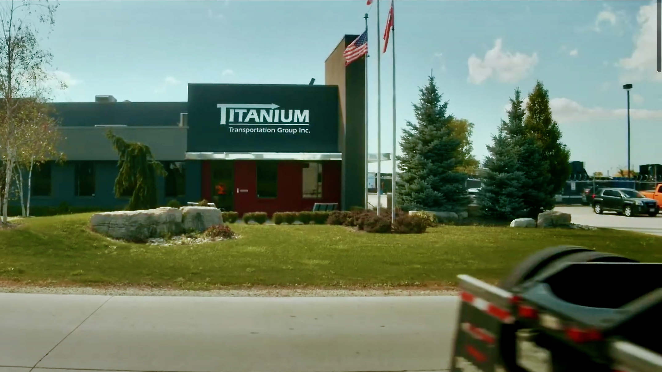 The outside of a Titanium Transportation Group office with a US and Canadian flag flying in front of it.