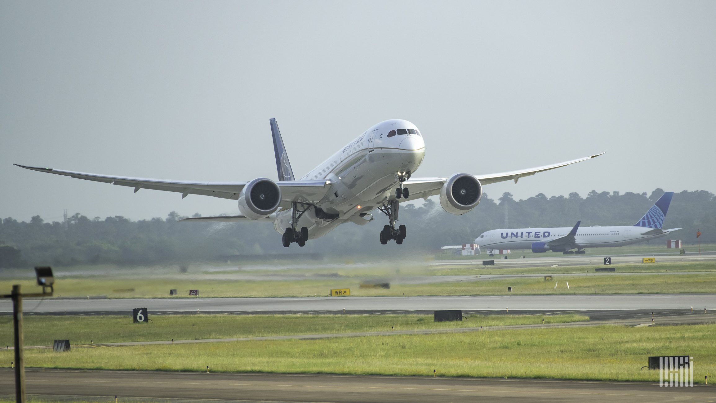 Front view of a plane taking off, with a United Airlines plane in the background.