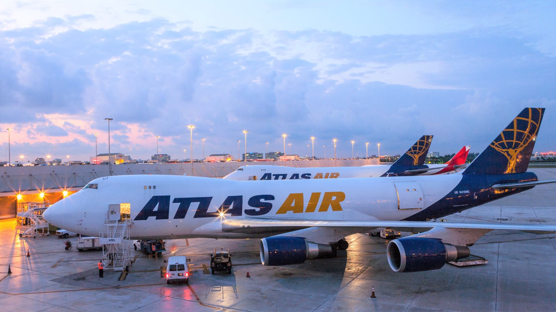 Atlas Air jumbo jets with blue and gold lettering sit on tarmac at dawn.