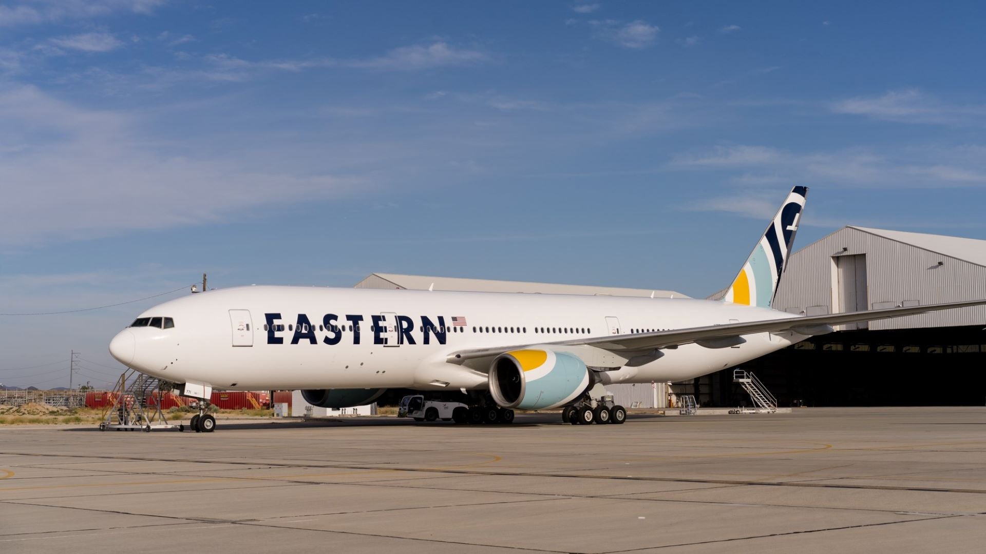 An Eastern Airlines jet on tarmac in front of a hangar building.