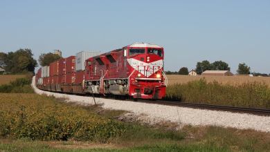 A photograph of a train rolling through a grassy field.