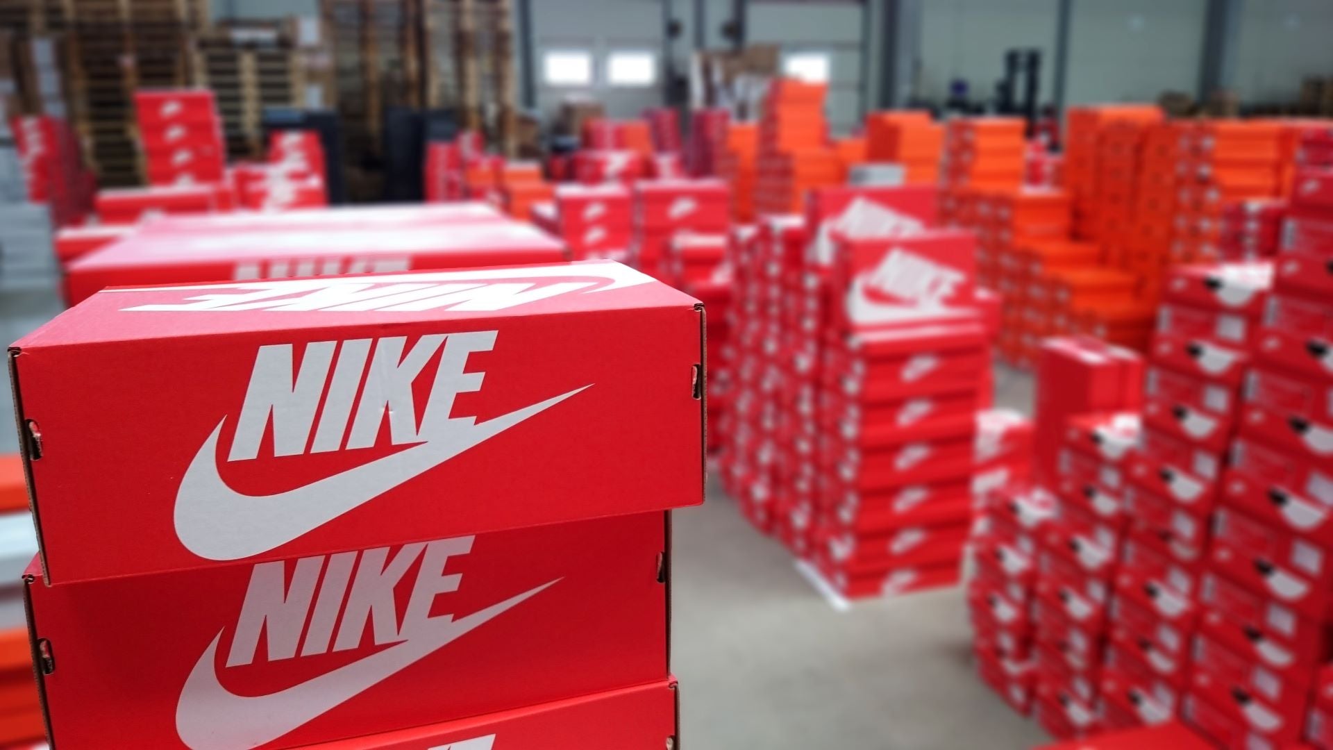 Stacks of red Nike shoe boxes in a warehouse.