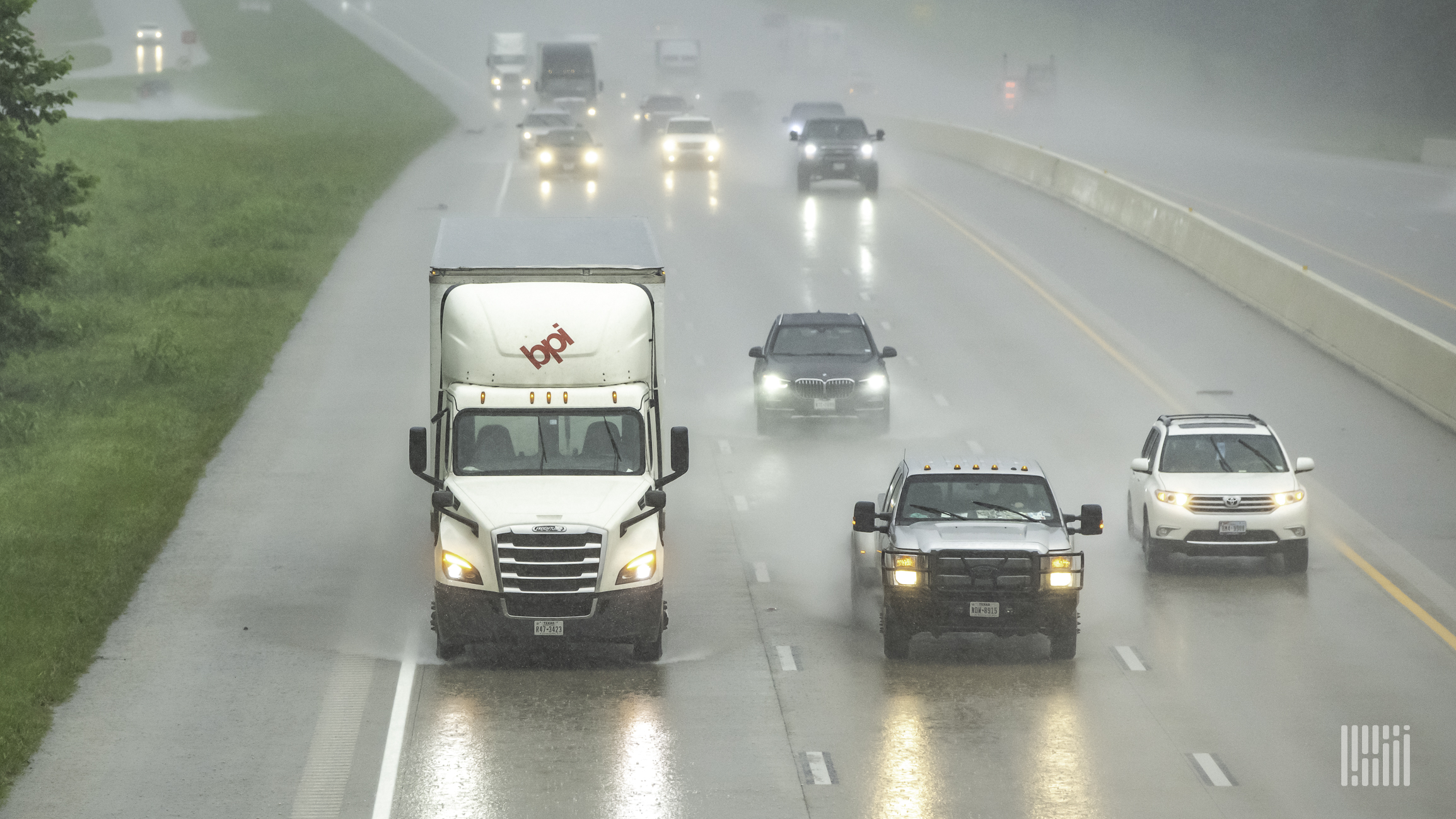 Trucks and cars on a highway during heavy rain.