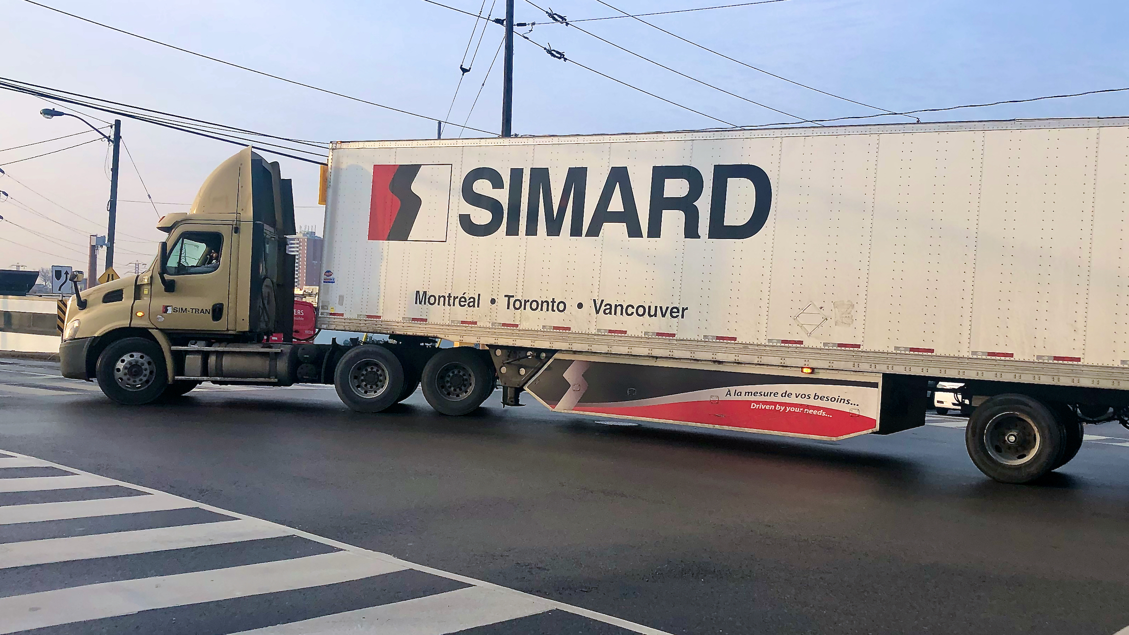 A tractor-trailer logo SIMARD makes a turn on a street to illustrate an article about the Canadian election.
