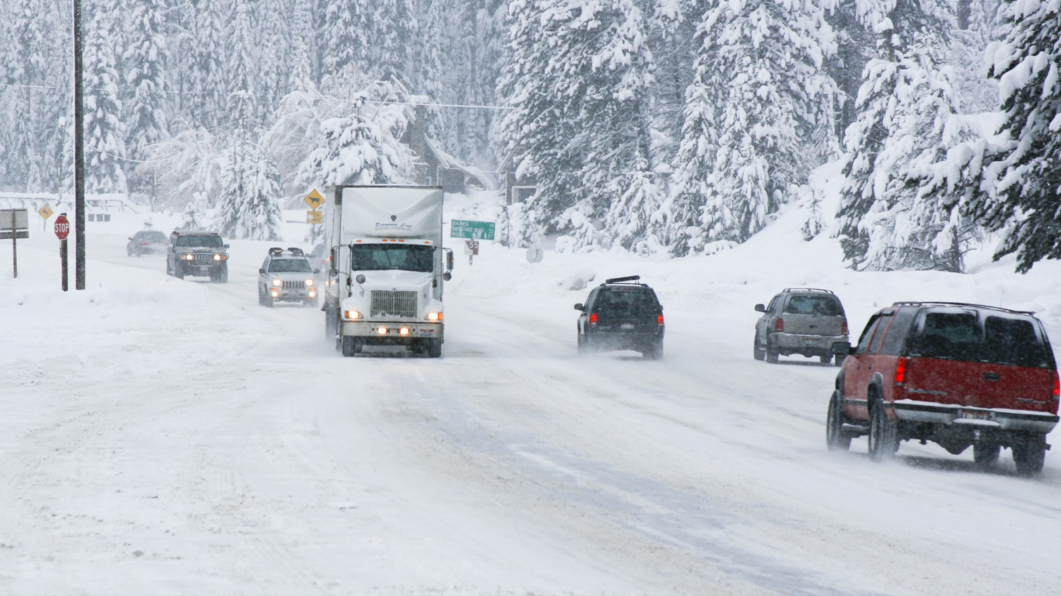 Cars and tractor-trailers on a snowy highway.