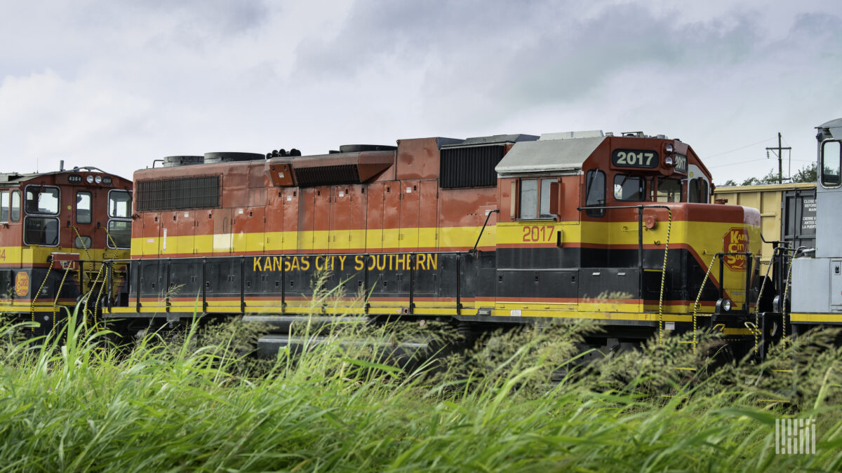 A photograph of a Kansas City Southern locommotive traveling across a grassy field.A