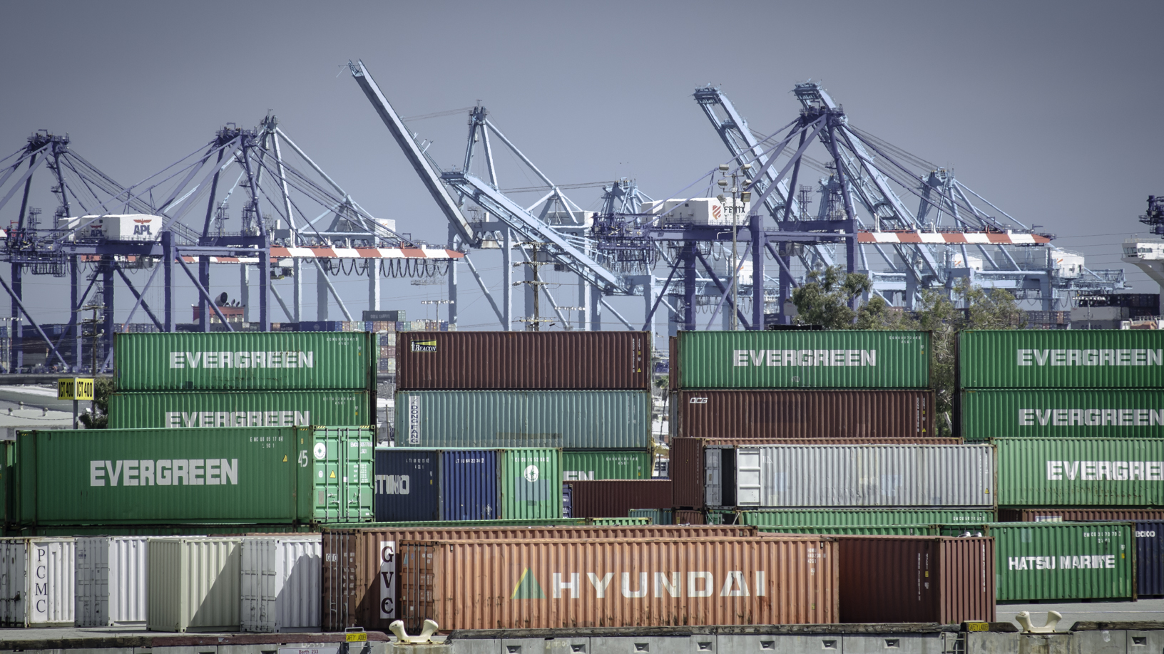 Containers and cranes in the background at a big port.