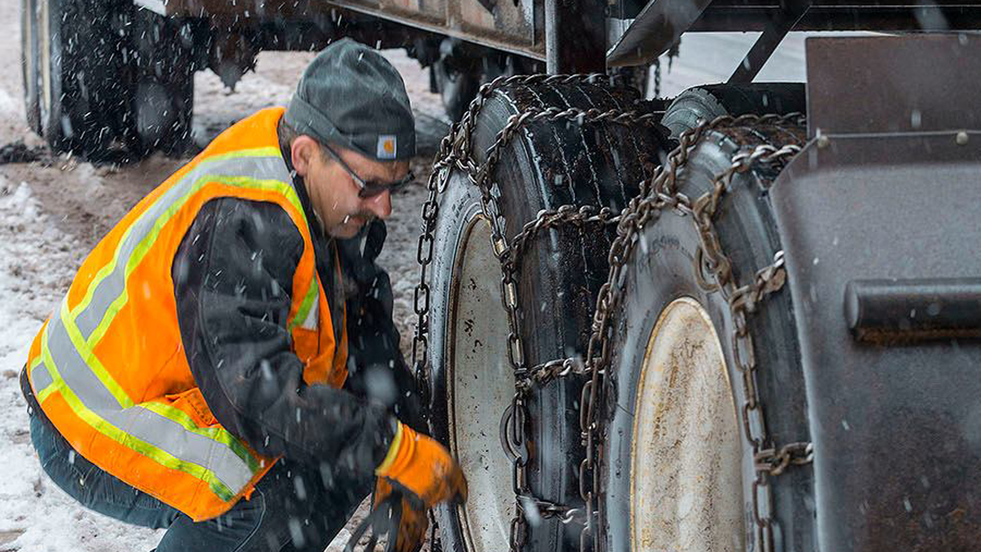 Truck driver chaining up in the snow.