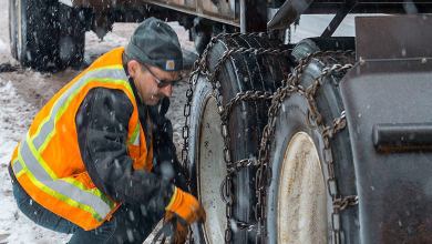 Truck driver chaining up in the snow.