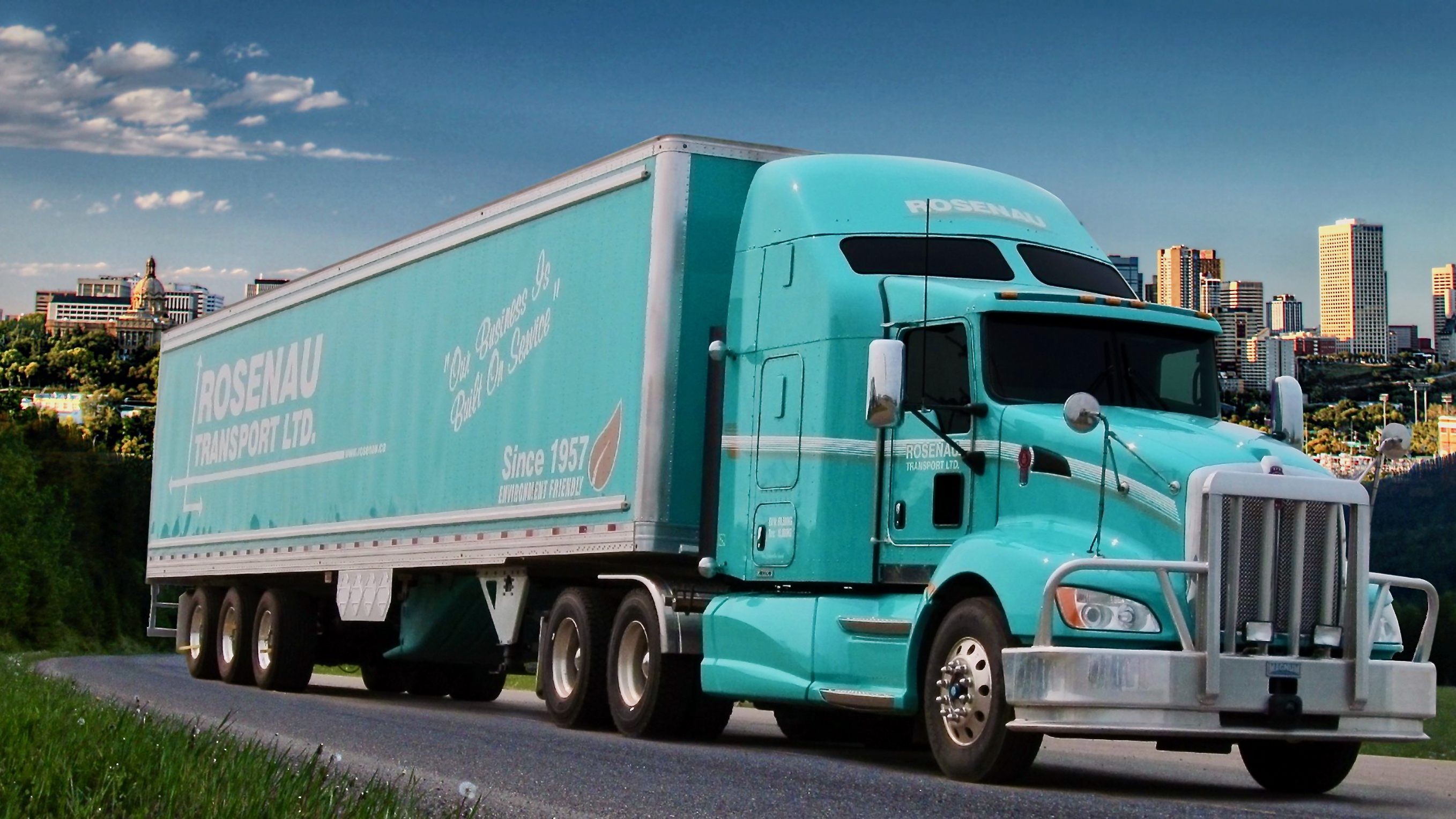 A tractor-trailer of Rosenau Transport against a city background.